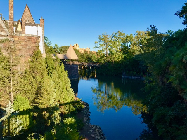 The Harry Potter Castle is surrounded by trees and a river and it is located at the Islands of Adventure in Orlando