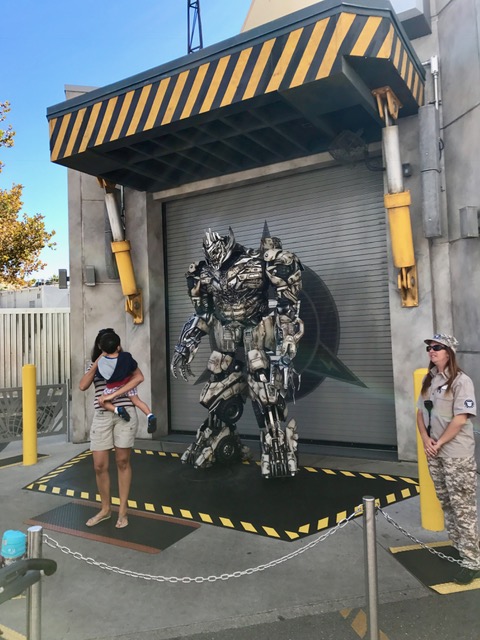 a women with her kid taking photos with Megatron incarnate, the fictional character in the Transformers movie