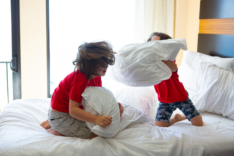 two boys having a pillow fight on a bed