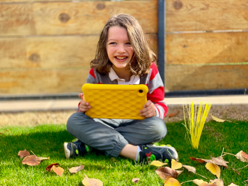 boy smiling sitting on grass with his kindle fire learning how to  Balance Kid's Screen Time