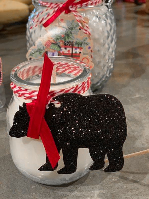 candle with red and white tie and sparkled paper bear attached