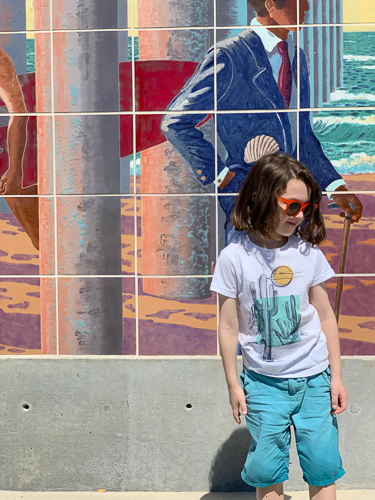 A girl wearing eyeglasses standing in front of street art in California.
