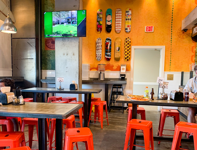 pizzaria restaurant with tables and orange chairs and skateboards on the wall at Oceanside, California
