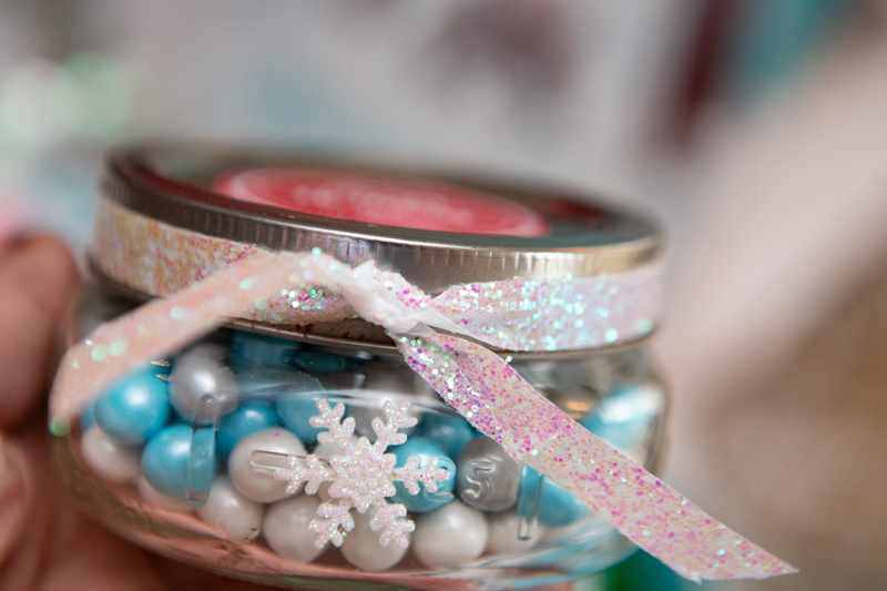 mason jar of white and blue candy with sparkly bow