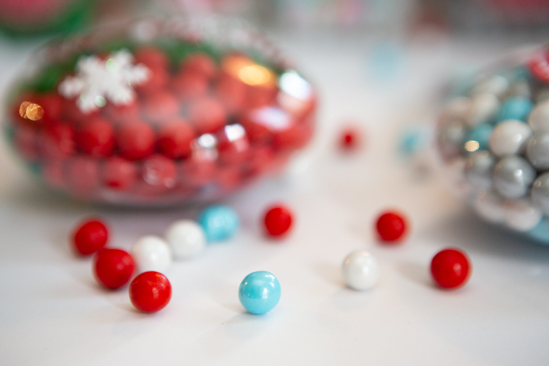 Christmas candy filled ornaments with red, white and blue sixlets next to them