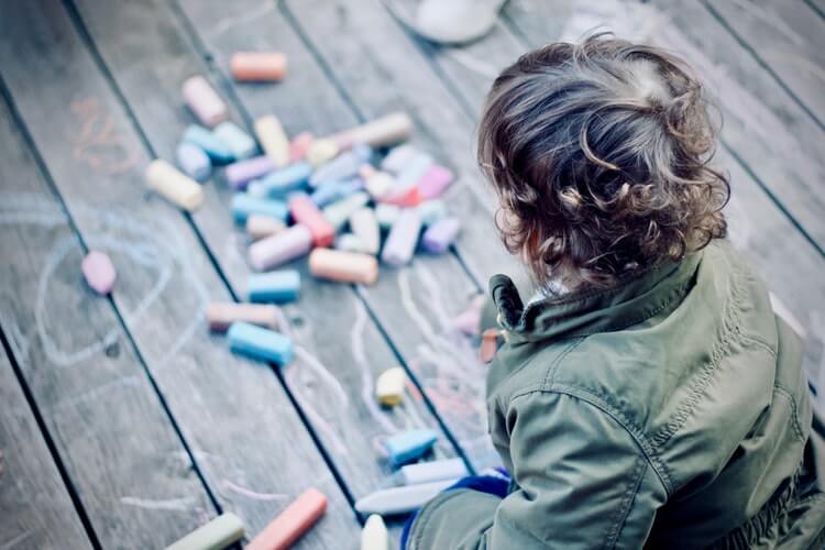 child looking at chalk on the floor