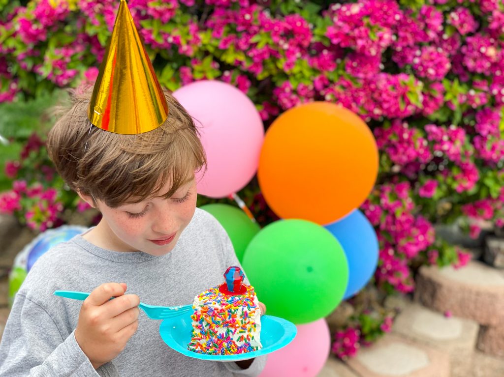Boy eating cake with sprinkles and ring pop on top