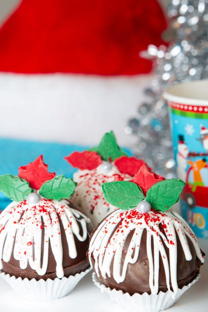 3 DIY Christmas Cocoa Bombs with green and red petals and red sprinkles for the Christmas Cocoa Bombs for the Holidays